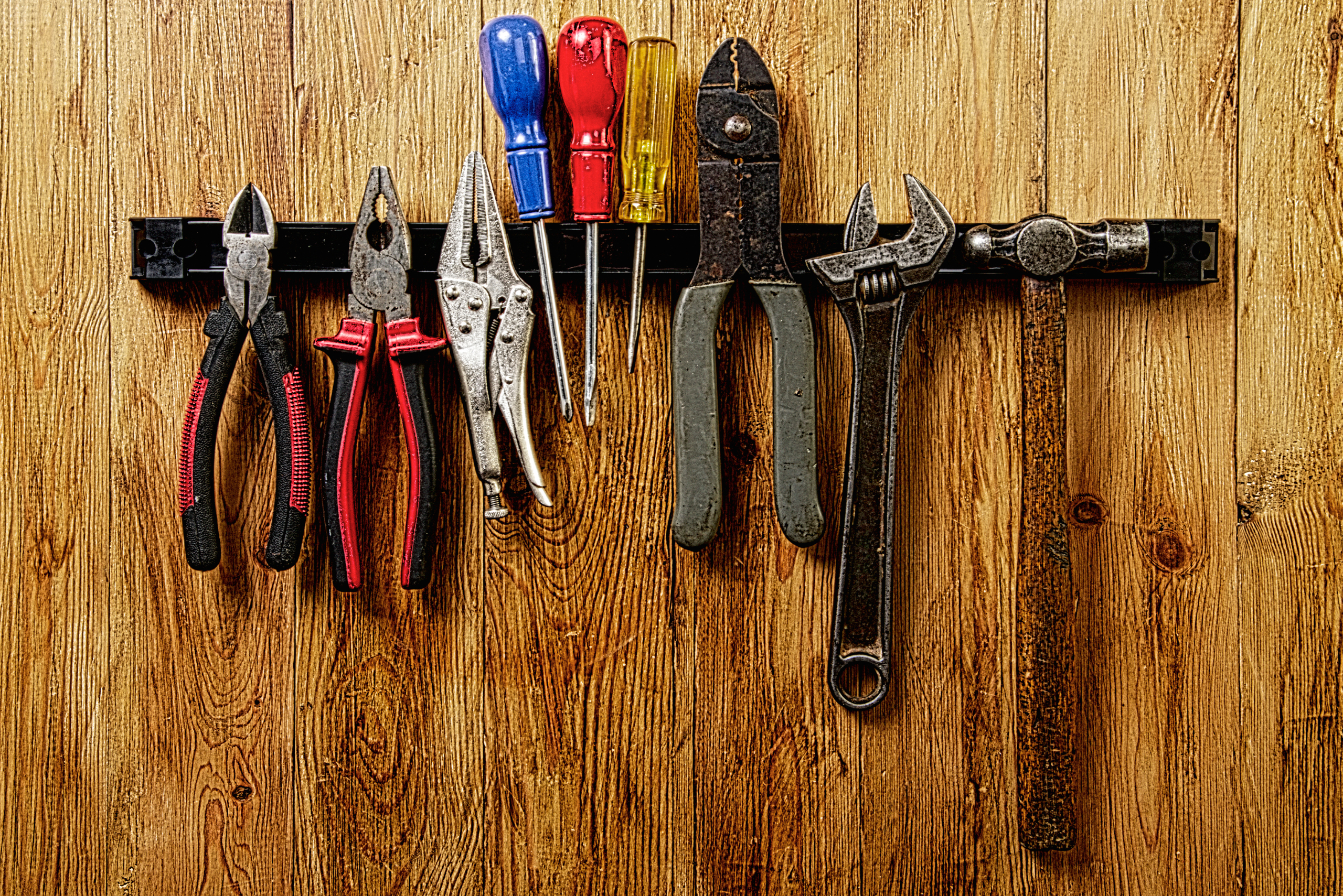 Magnetic strip holding up tools on the wall.