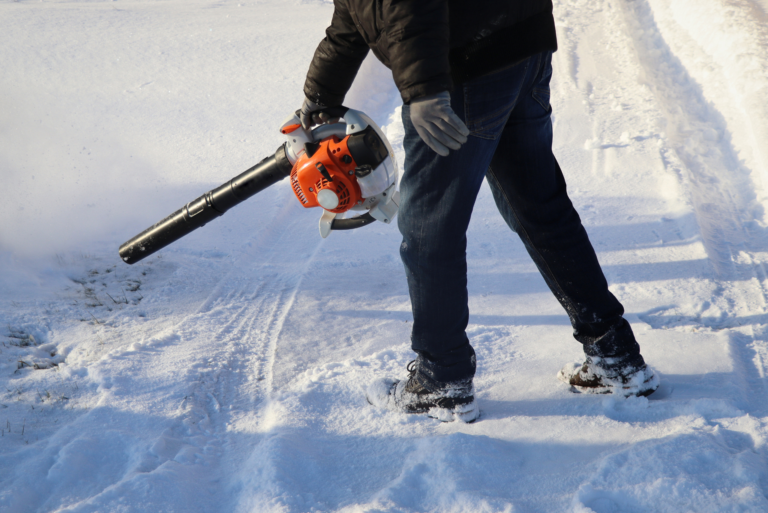 Man using leaf blower on snow.