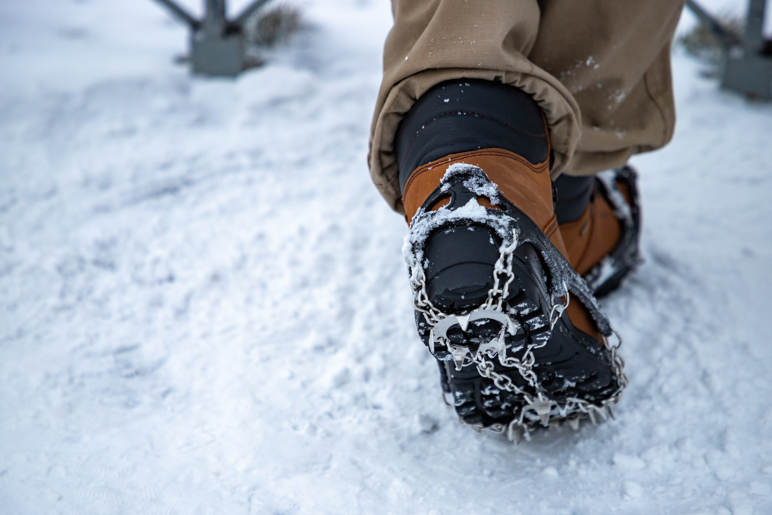 Closeup of someone's snow boots with chains.