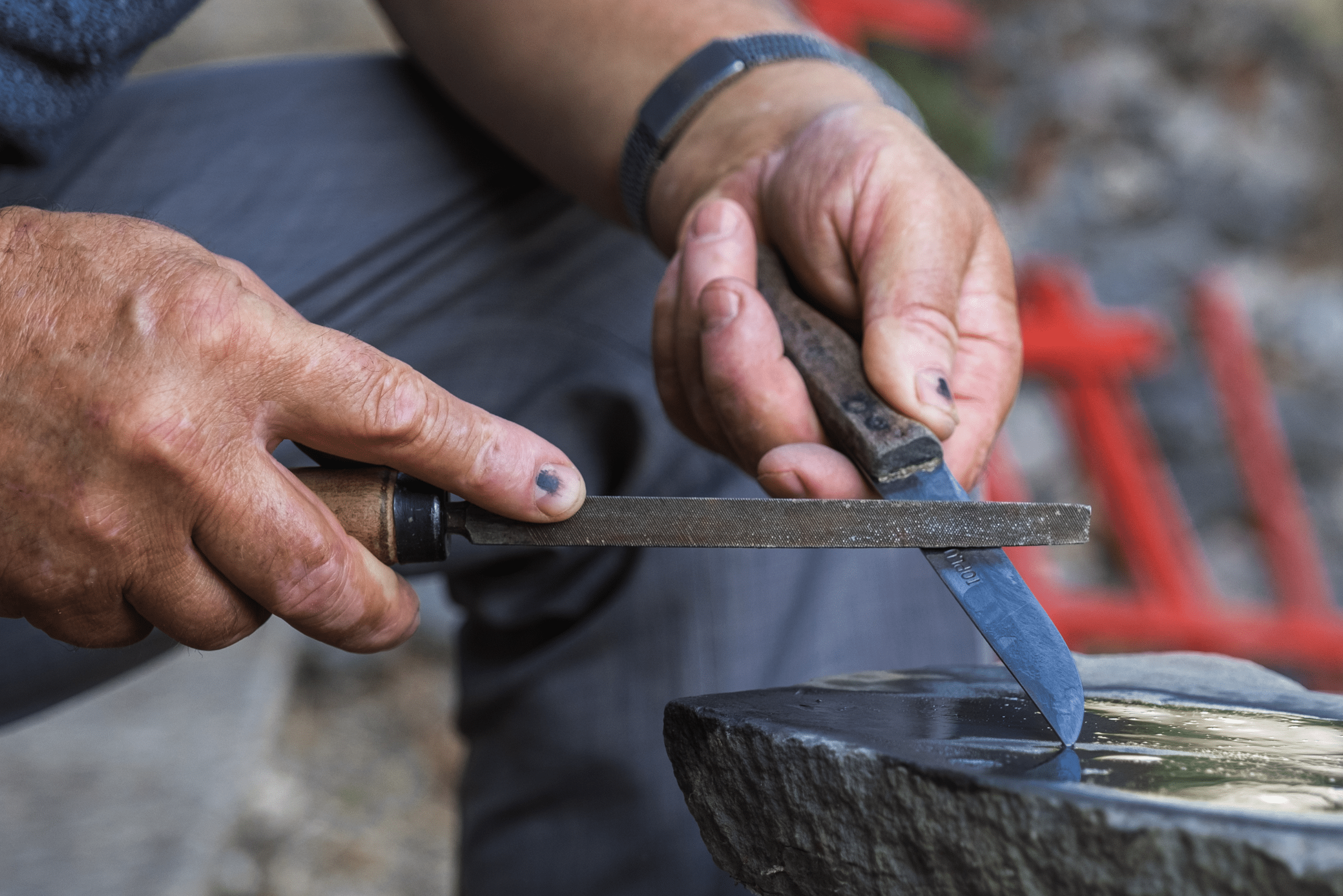 Man sharpening knife outdoors.