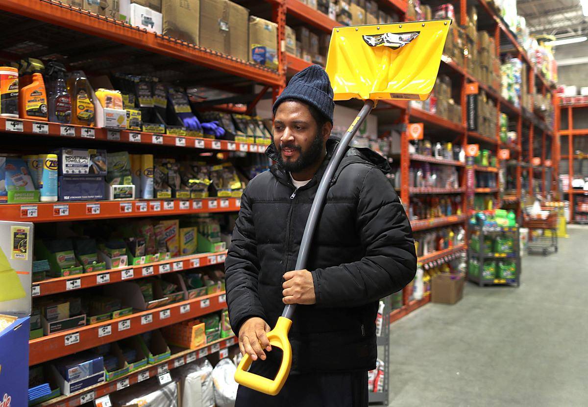 Man holding a yellow snow shovel.