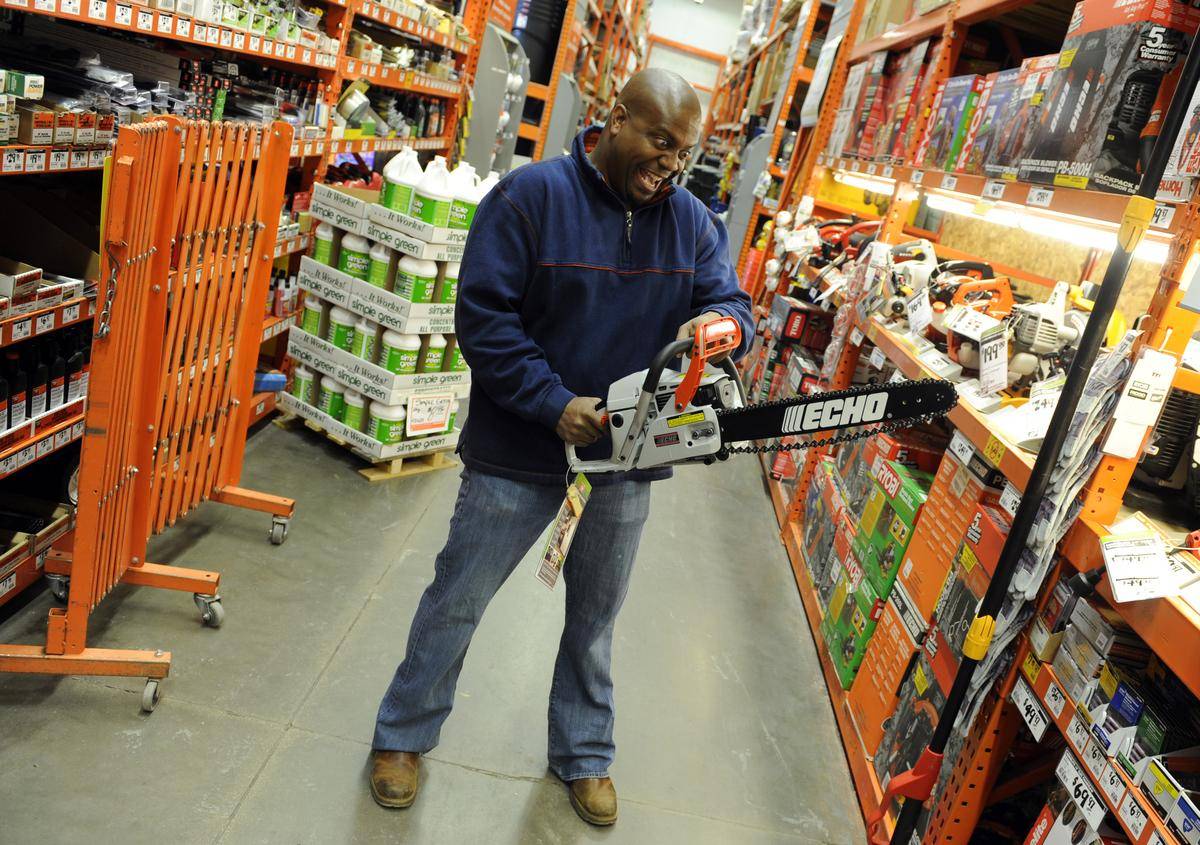 Man holding chainsaw in Home Depot aisle.