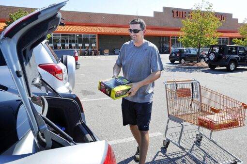 Person loading up Home Depot purchased items into truck of a car.