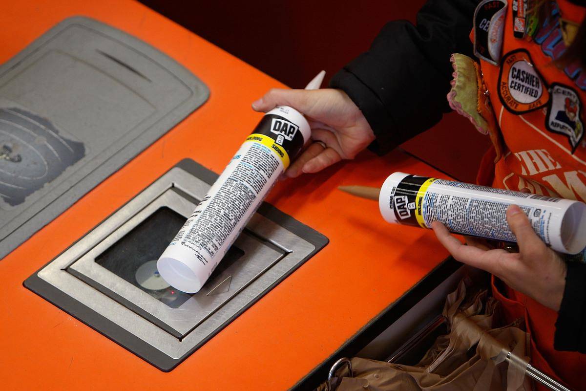 Person scanning caulking tubes at Home Depot checkout.