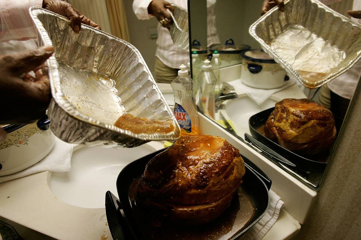 Hurricane Katrina evacuee Kathy Curry of New Orleans puts glaze on a ham as she prepares her Thanksgiving dinner in the bathroom of her hotel room at a Days Inn 