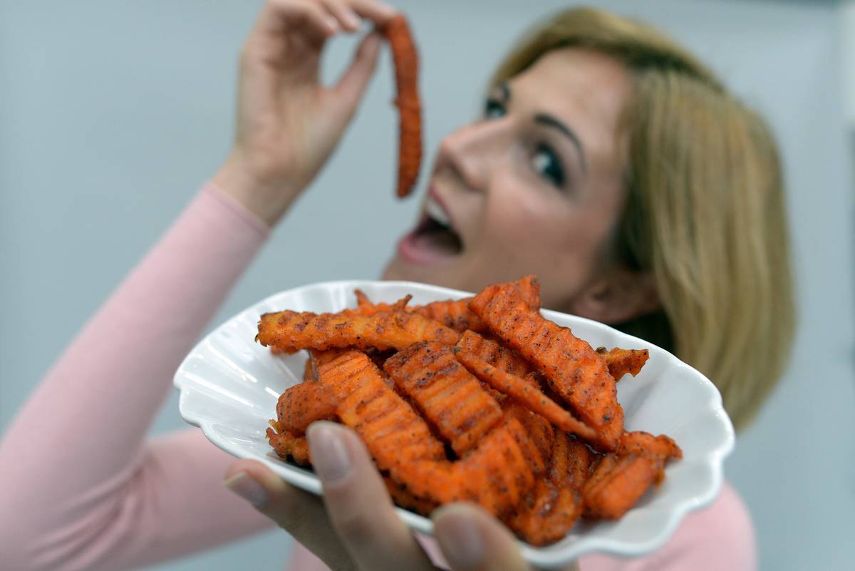 Model Myriel holds sweet potatoes products 