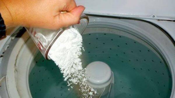 Putting baking soda in a washing machine.