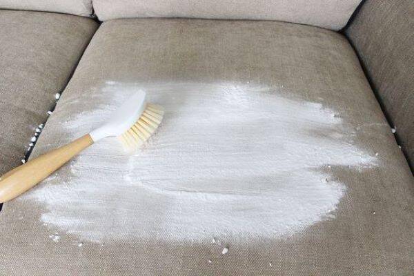 Cleaning couch with baking soda and brush.