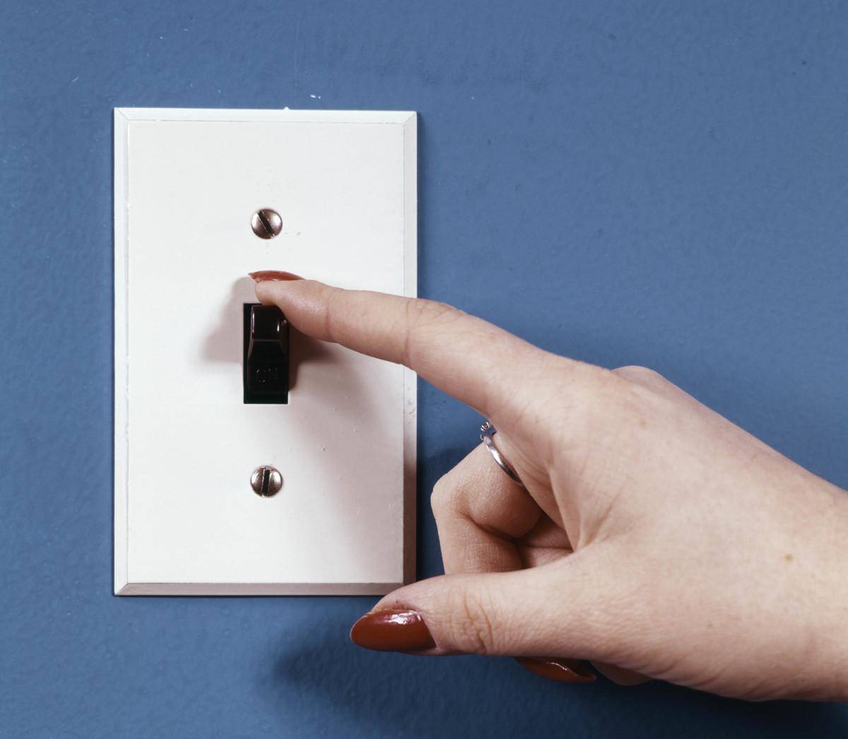 Closeup of a hand flickering power outlet off.