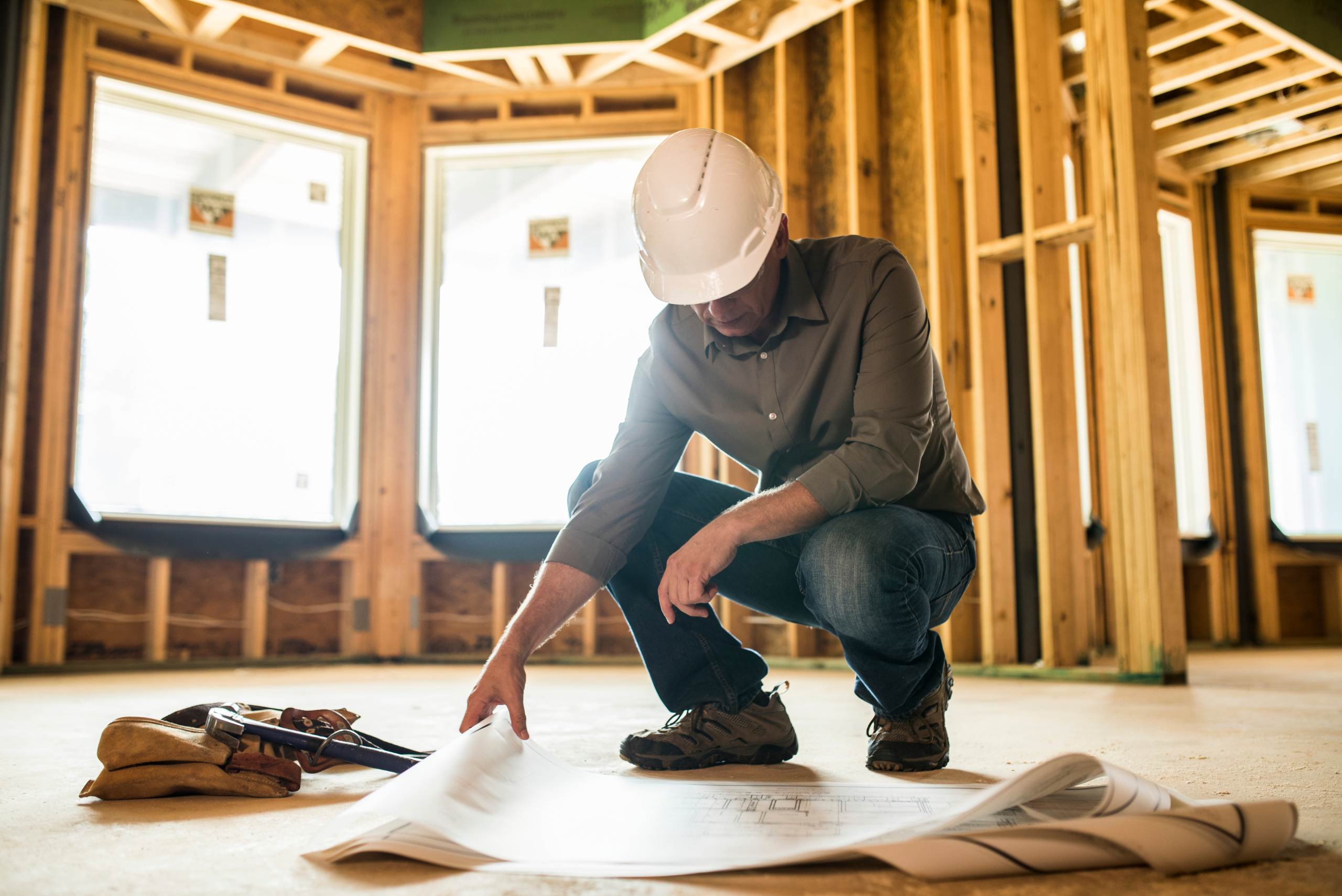 Contractor checking blueprints on the floor.