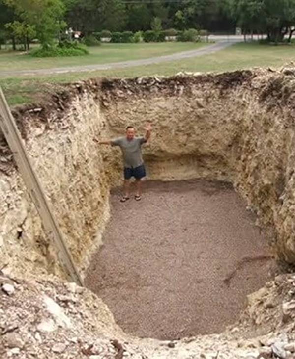 Man standing in a hole in his yard