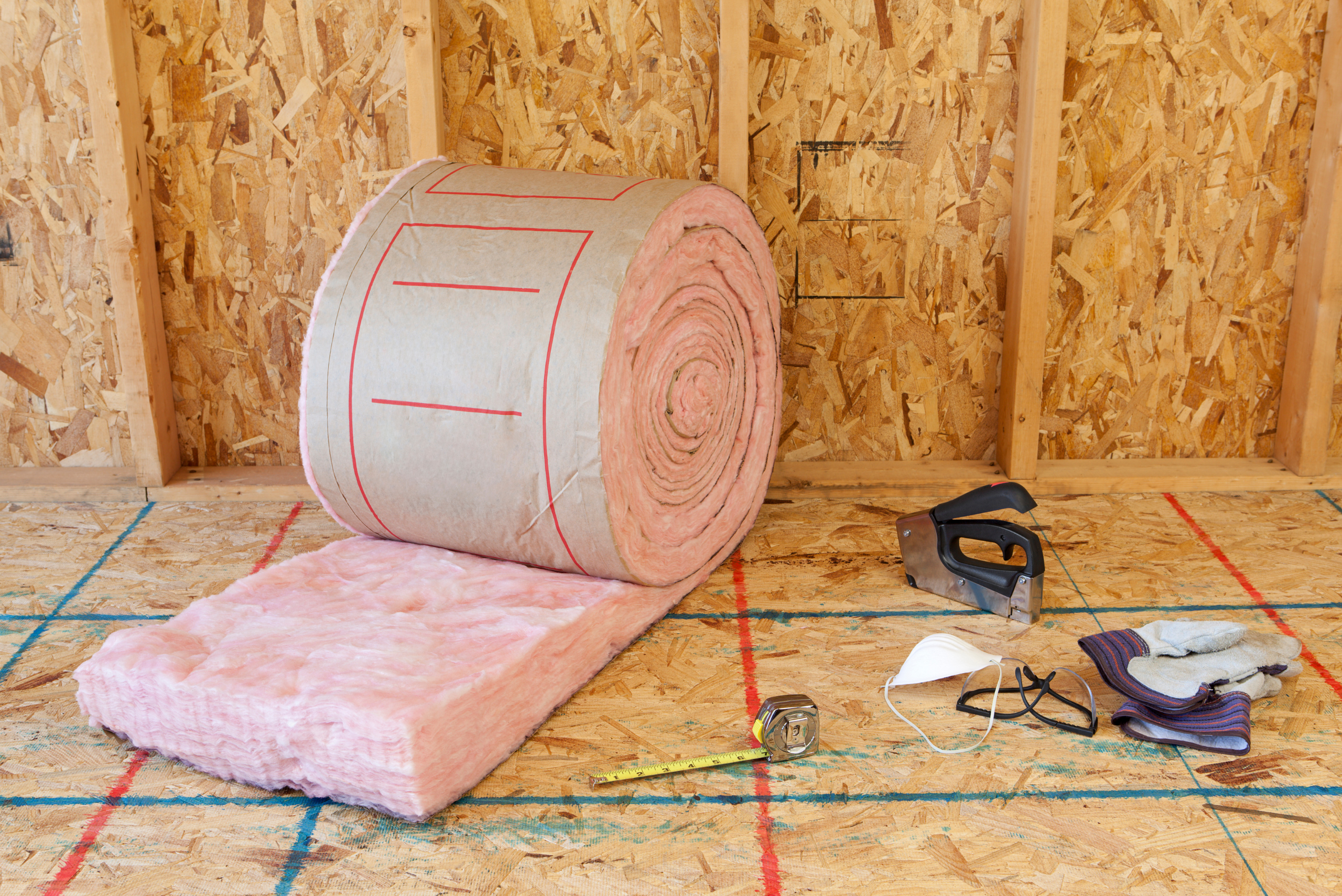 A roll of pink insulation material and assortment of tools.