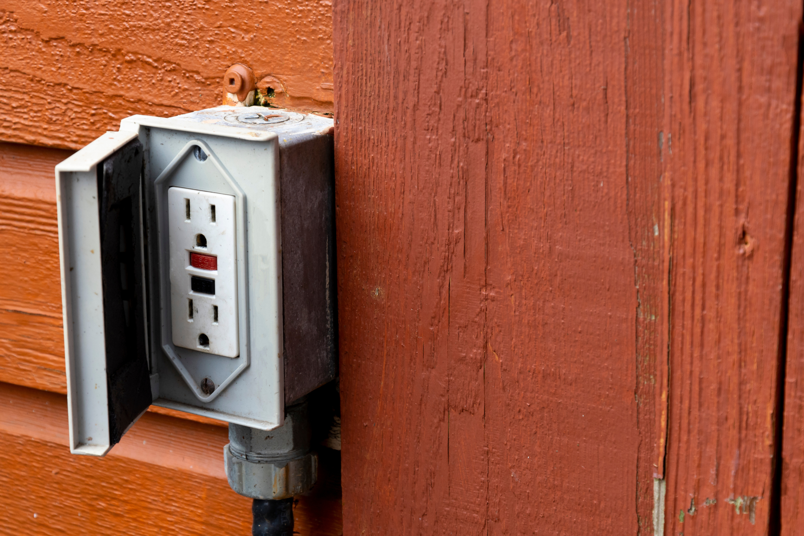 GFCI outlet with sealed box on wooden wall.