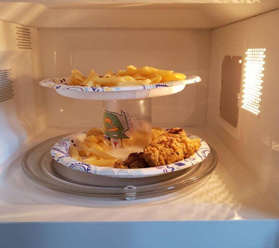 plates stacked on top of a cup to make room in a microwave