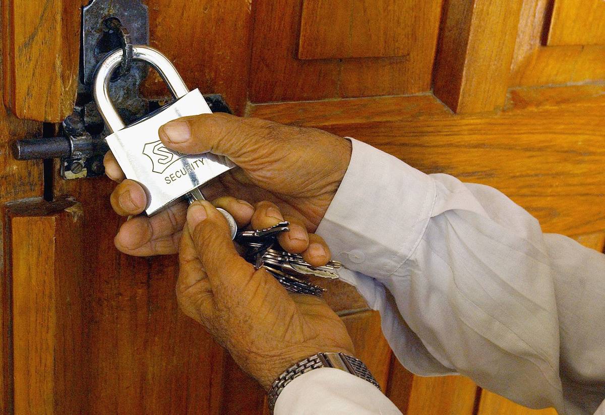 A man locks a door with a padlock.