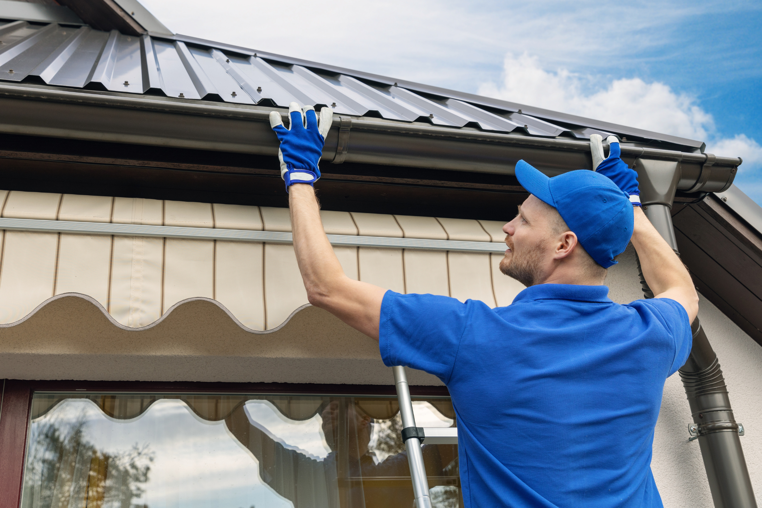 Worker installing gutter onto a house.