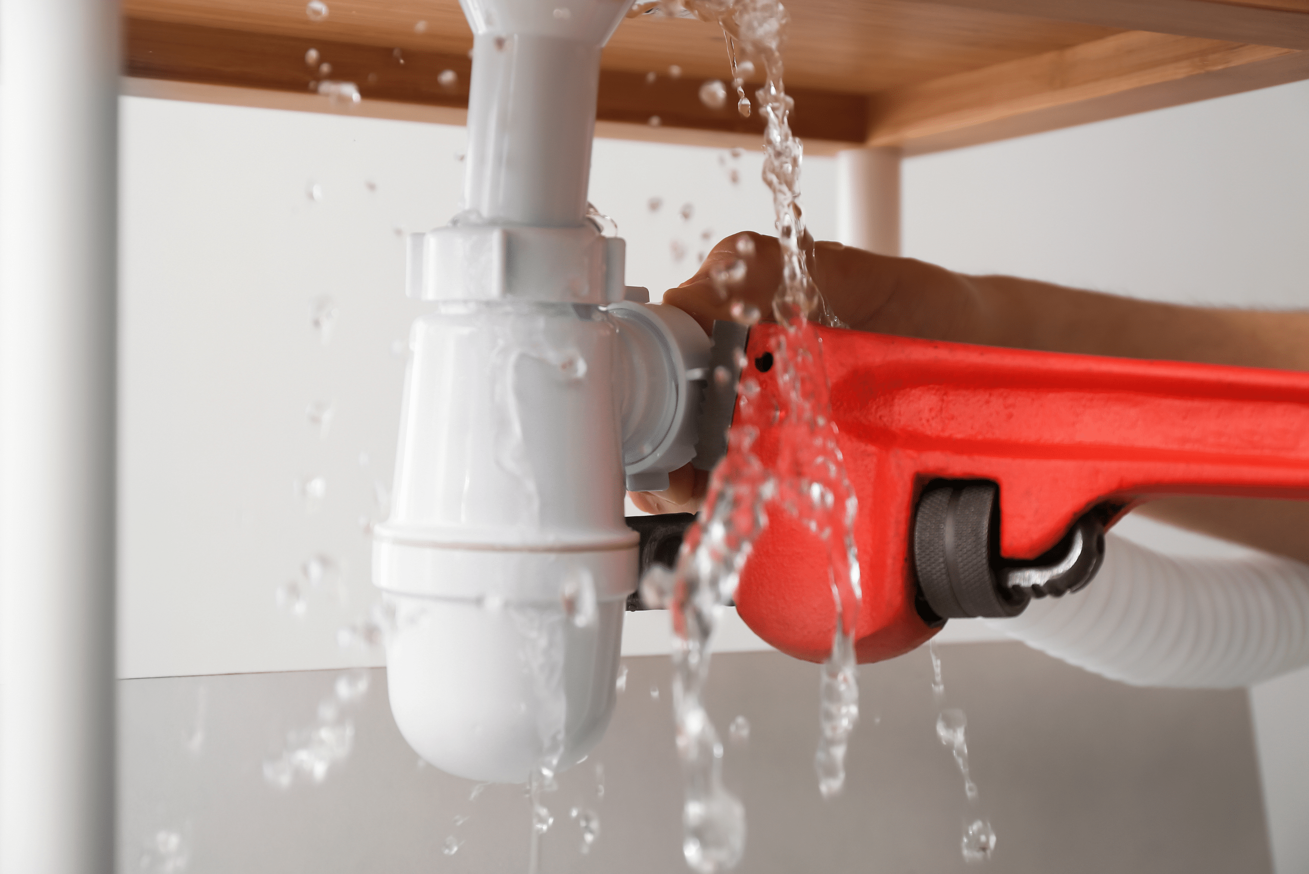 Adjustable wrench on piping that's leaking water under the sink.