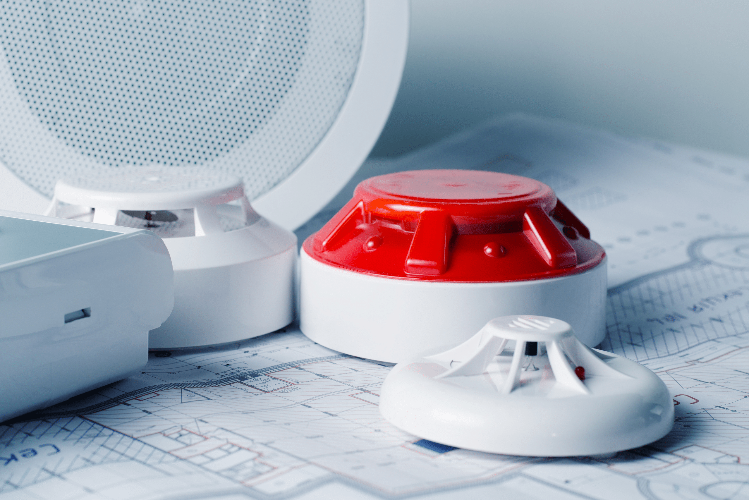 Red and white smoke alarm on top of blueprints.