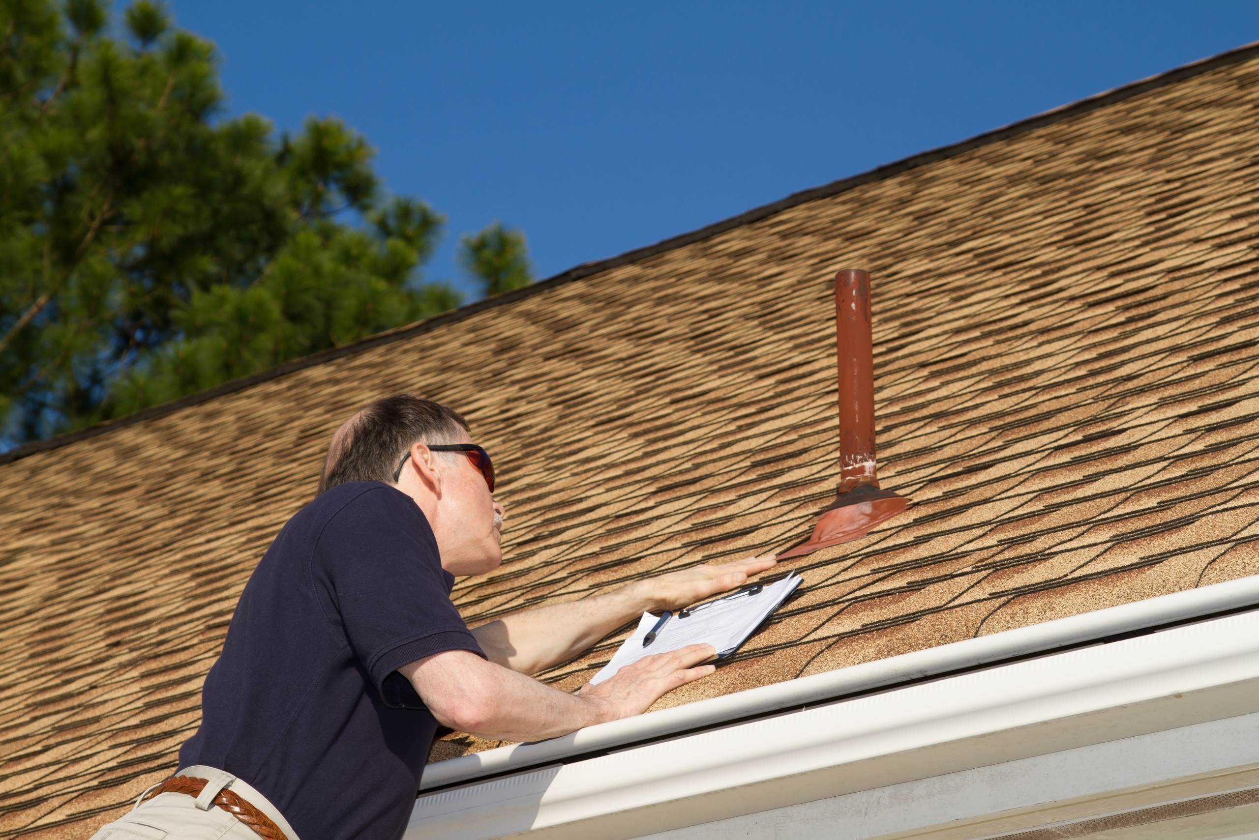 Man inspecting the vent on a house's roof.