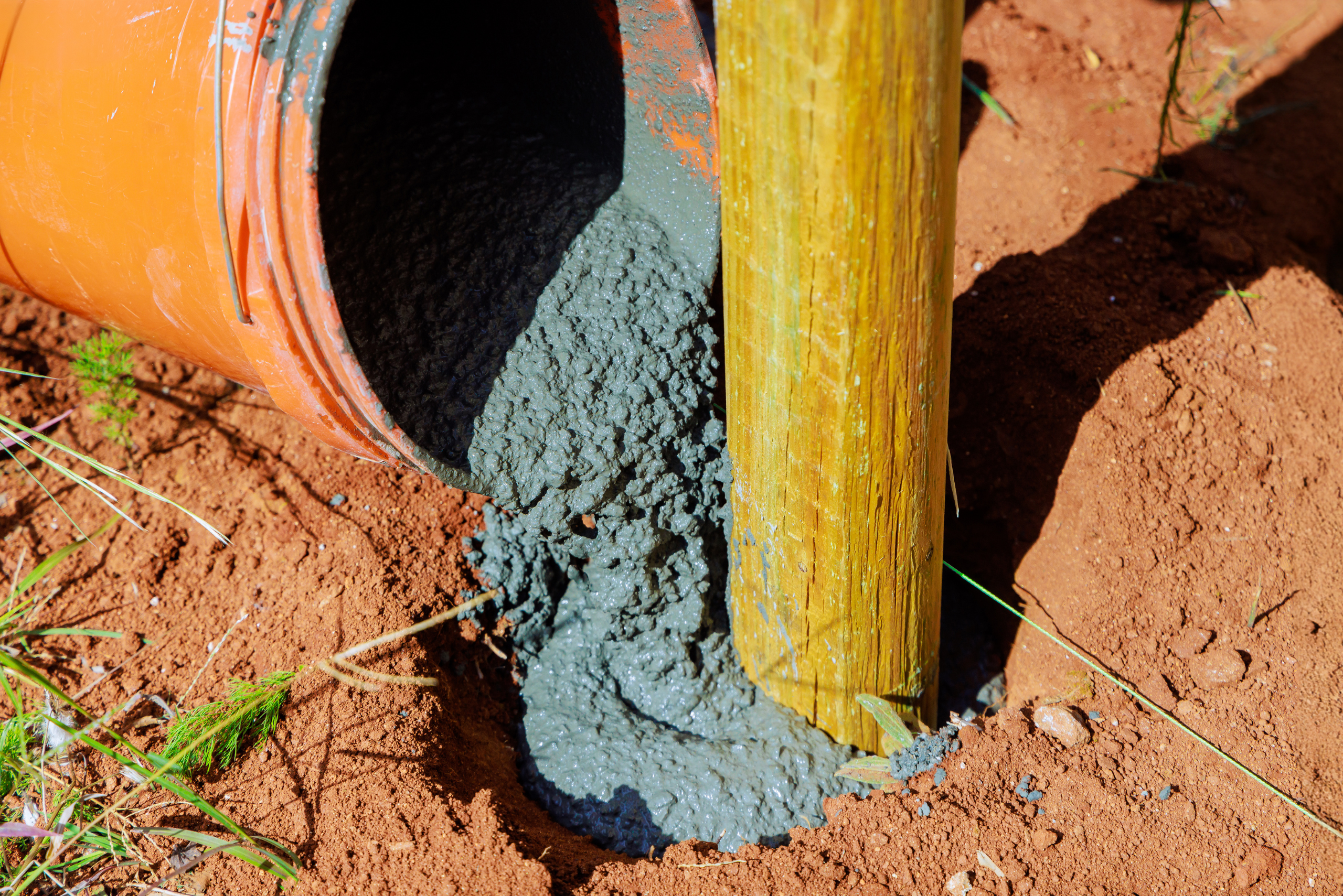 Pouring cement around the post of a mailbox.