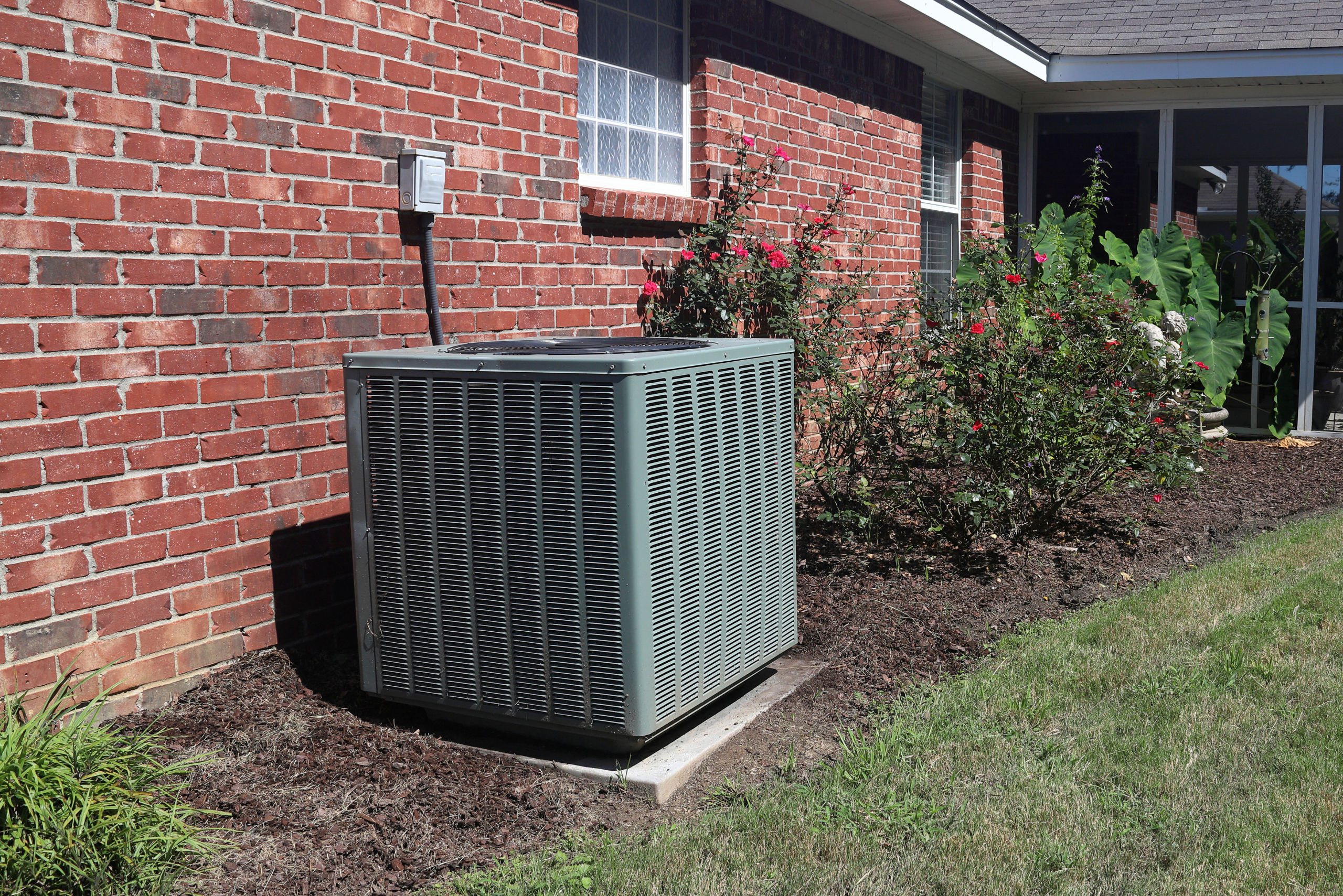 HVAC unit outside of a red brick house.