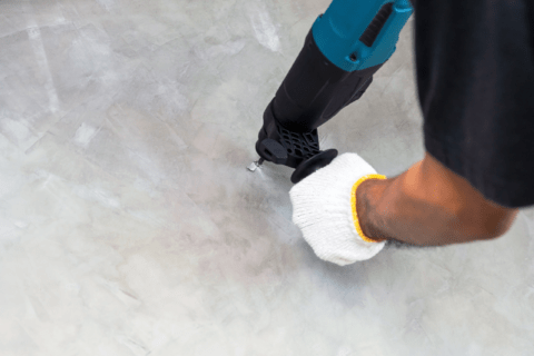 Man using a drill to make a hole in concrete.