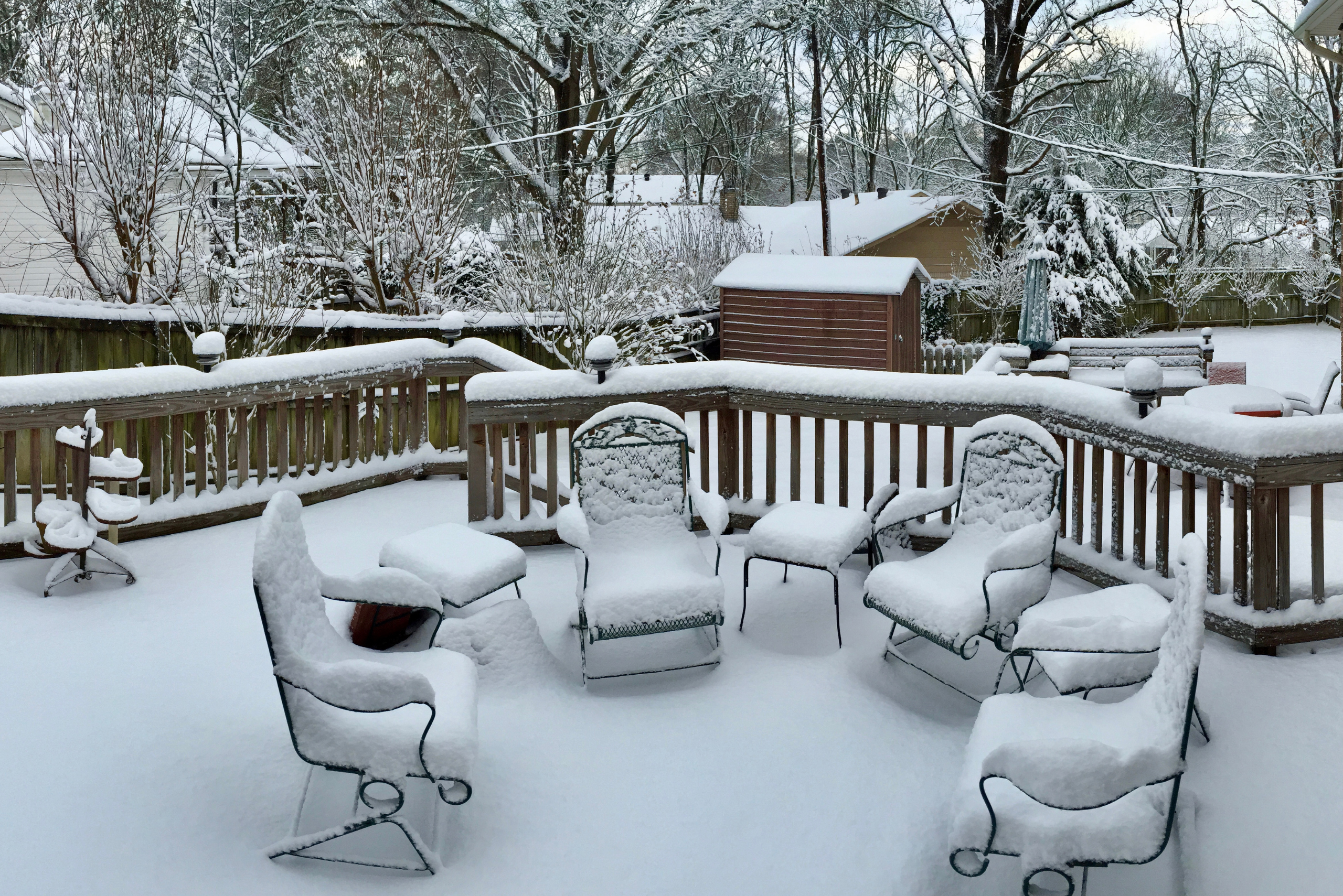 Outdoor furniture and deck covered in heavy snow.