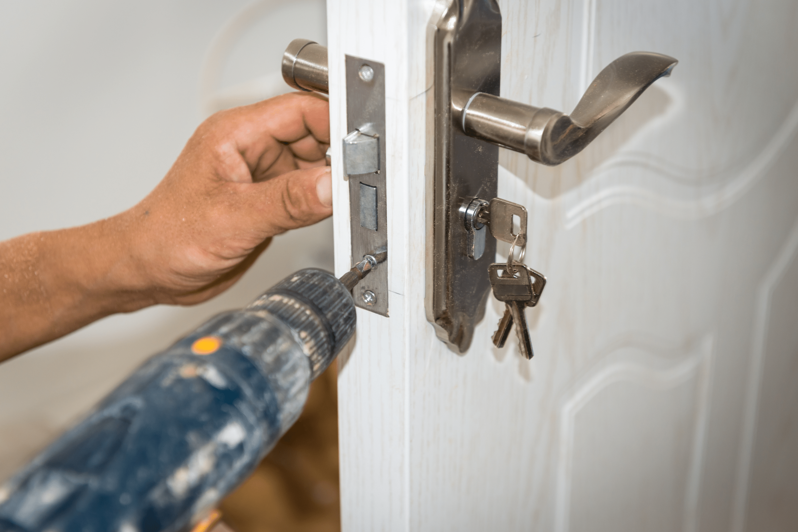 Closeup of a drill securing door lock hardware.