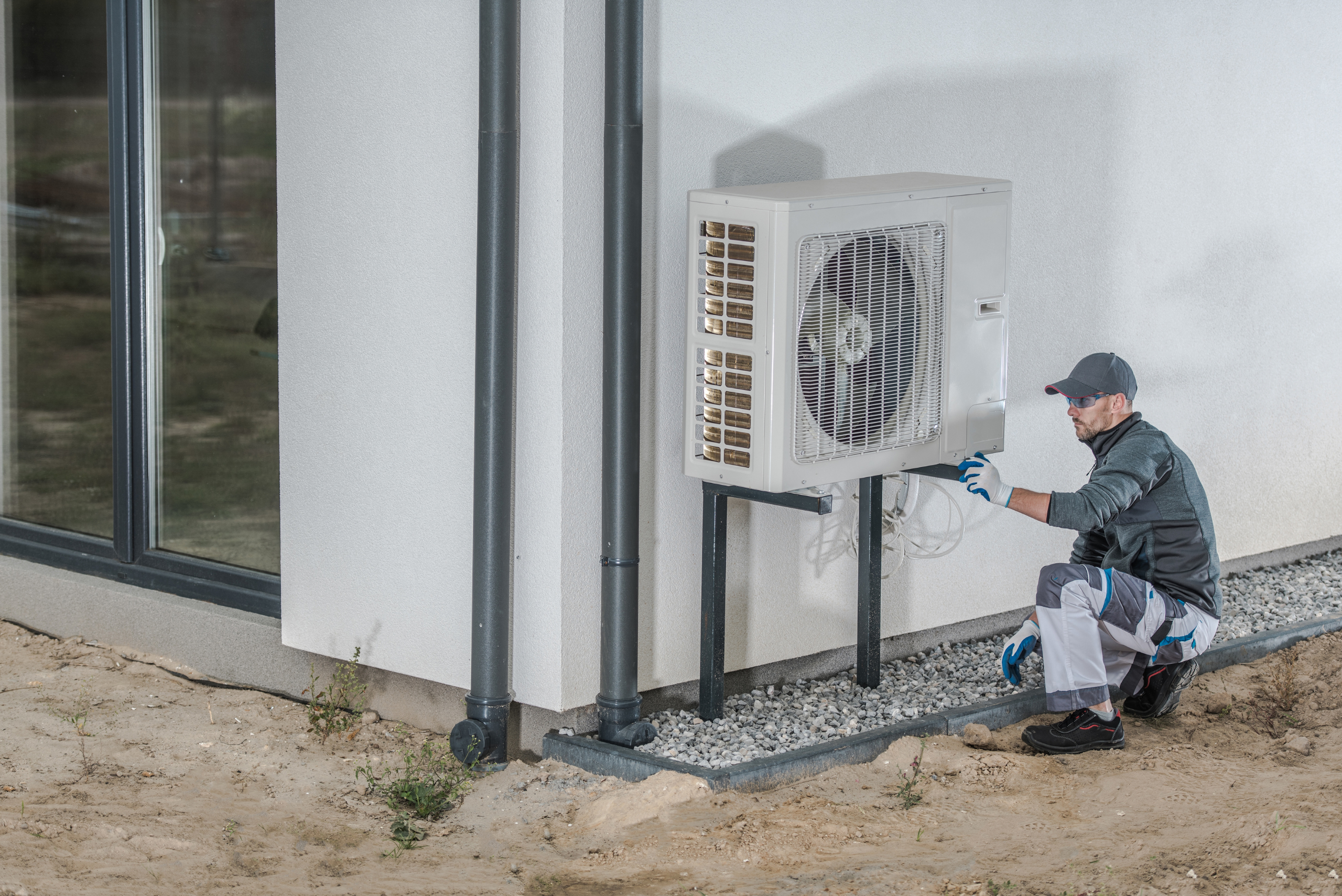 Worker inspecting a heat pump of a house.