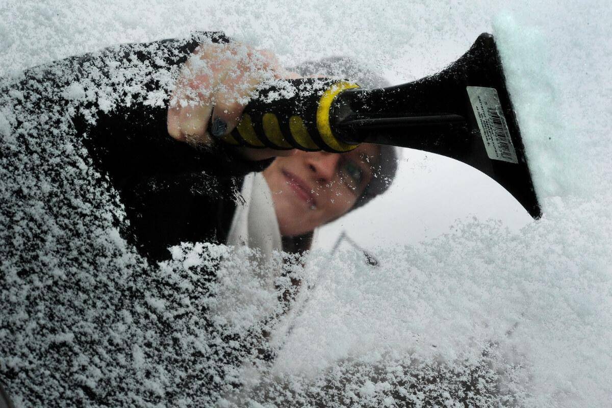 Person clearing icy windshield.