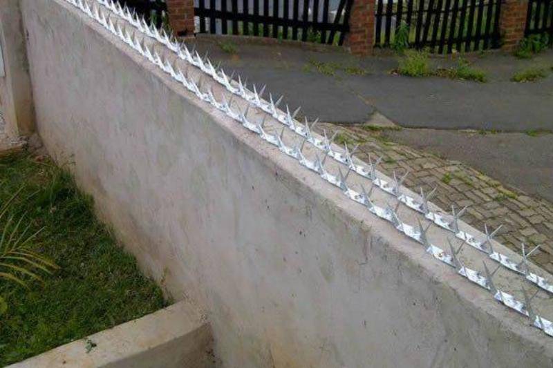 Small spikes are installed on top of a concrete fence to prevent people from climbing over it.