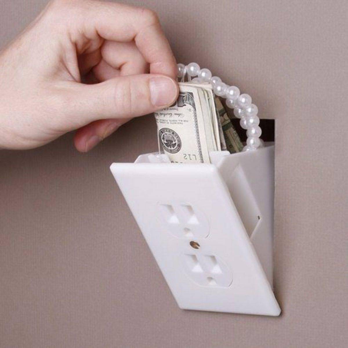 A person takes money and a bracelet out of a fake outlet.