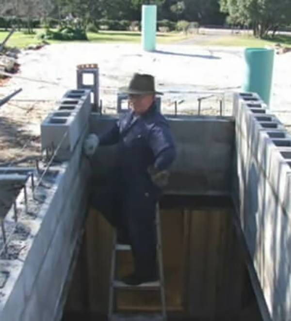 Person standing on a ladder around concrete blocks.