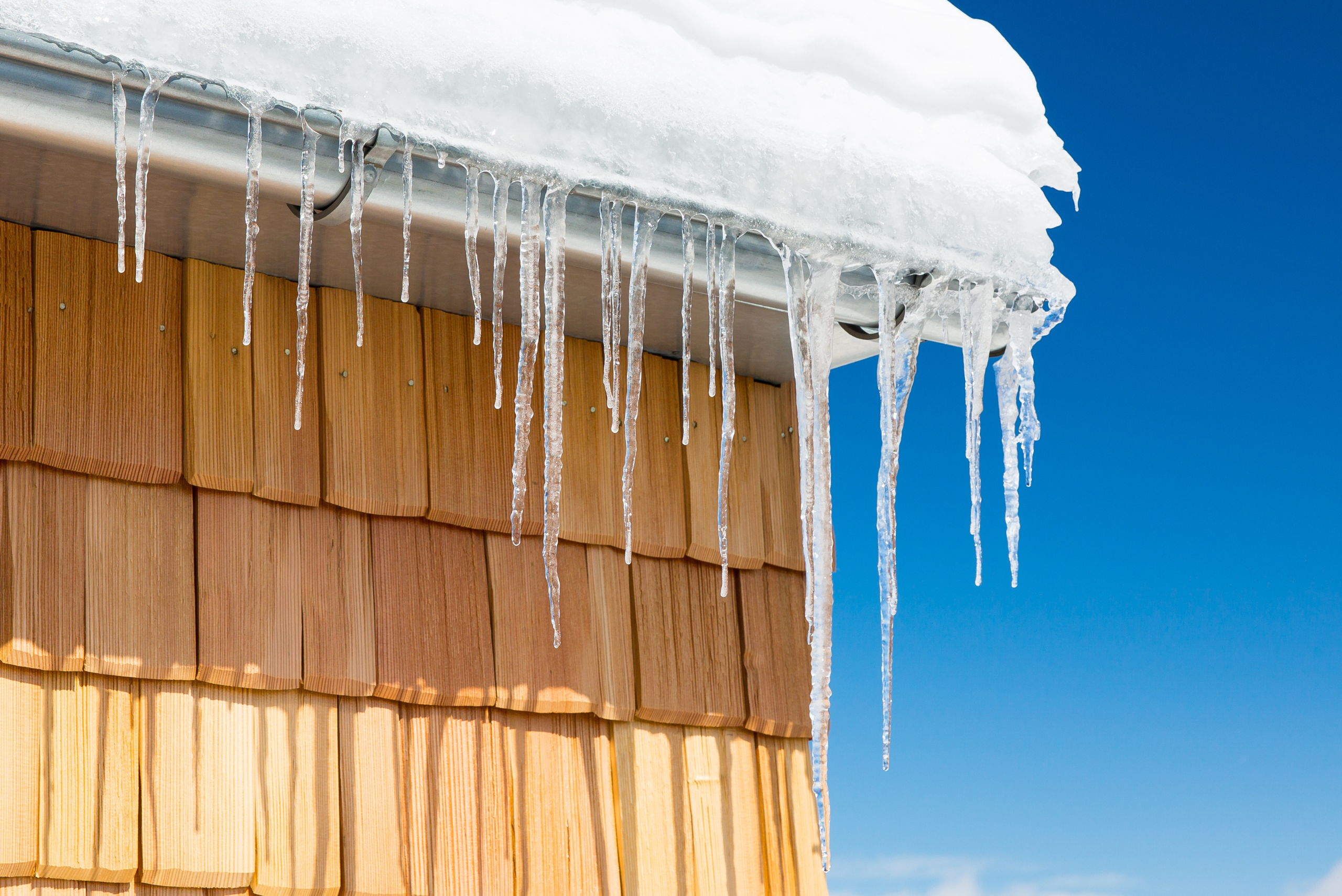 Ice dams on top of a house roof.