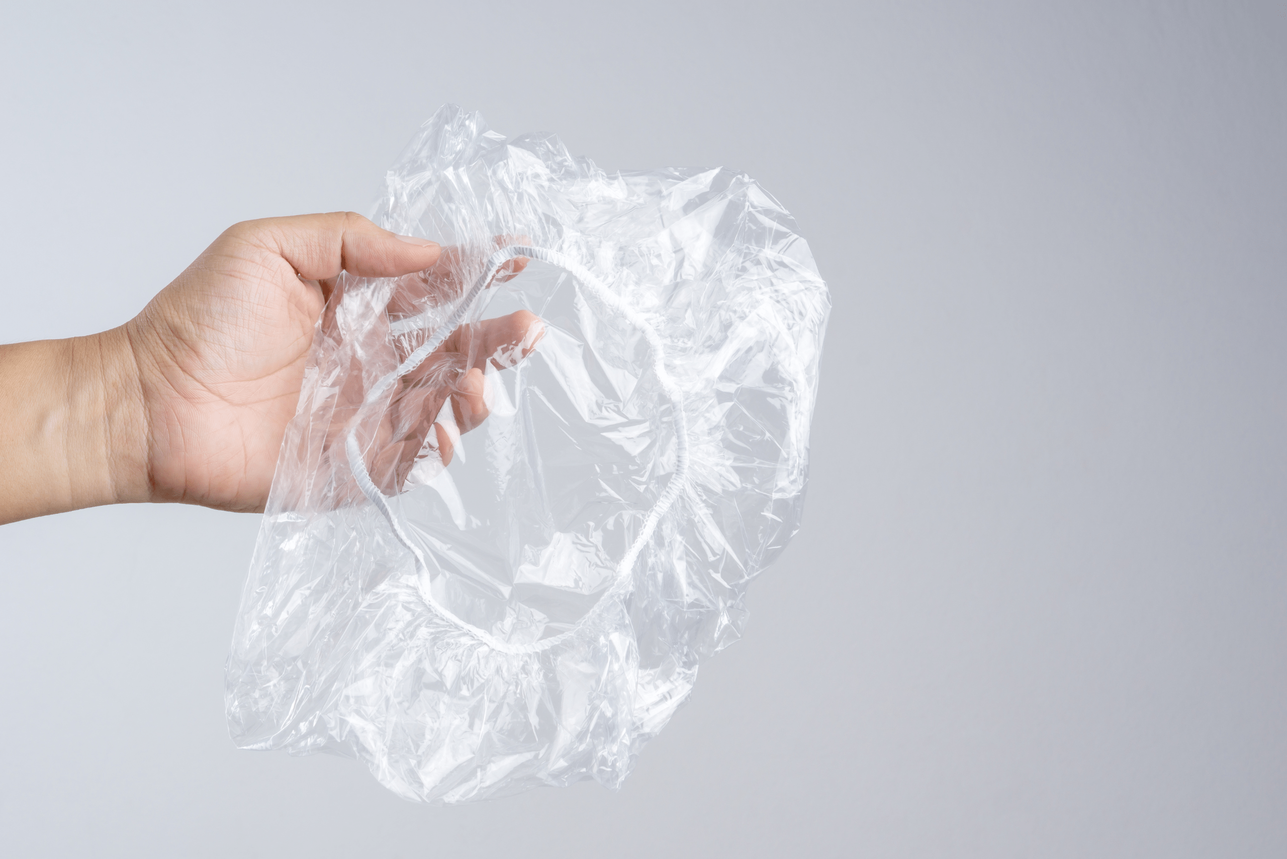 Person's hand holding a shower cap.