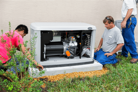 Three men installing a home backup generator.