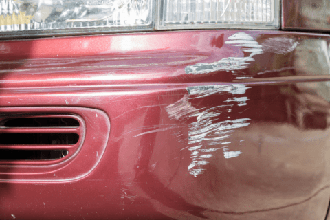 Red car with scratches on its bumper.