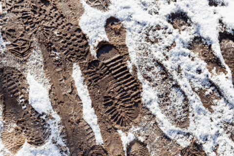 Foot prints in muddy lawn with snow.