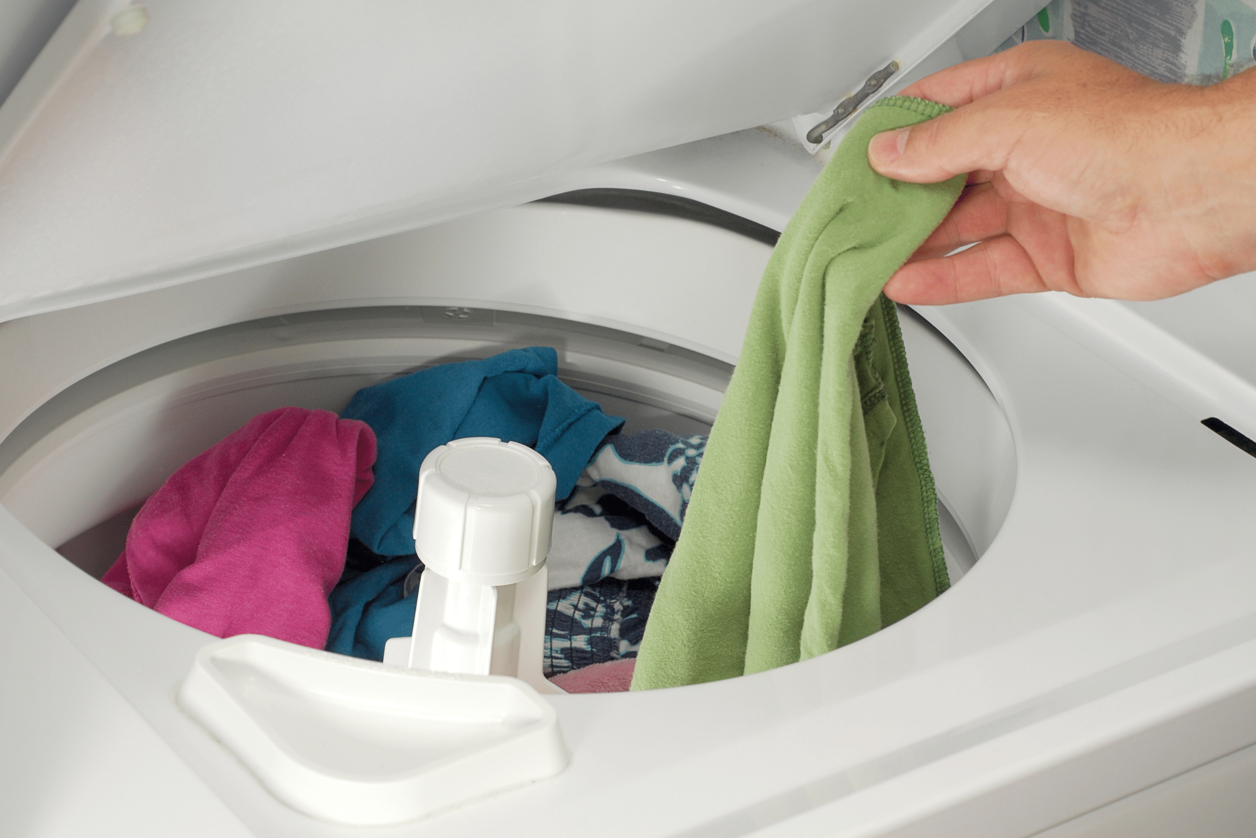 Person's hand pulling out clothes from washing machine.