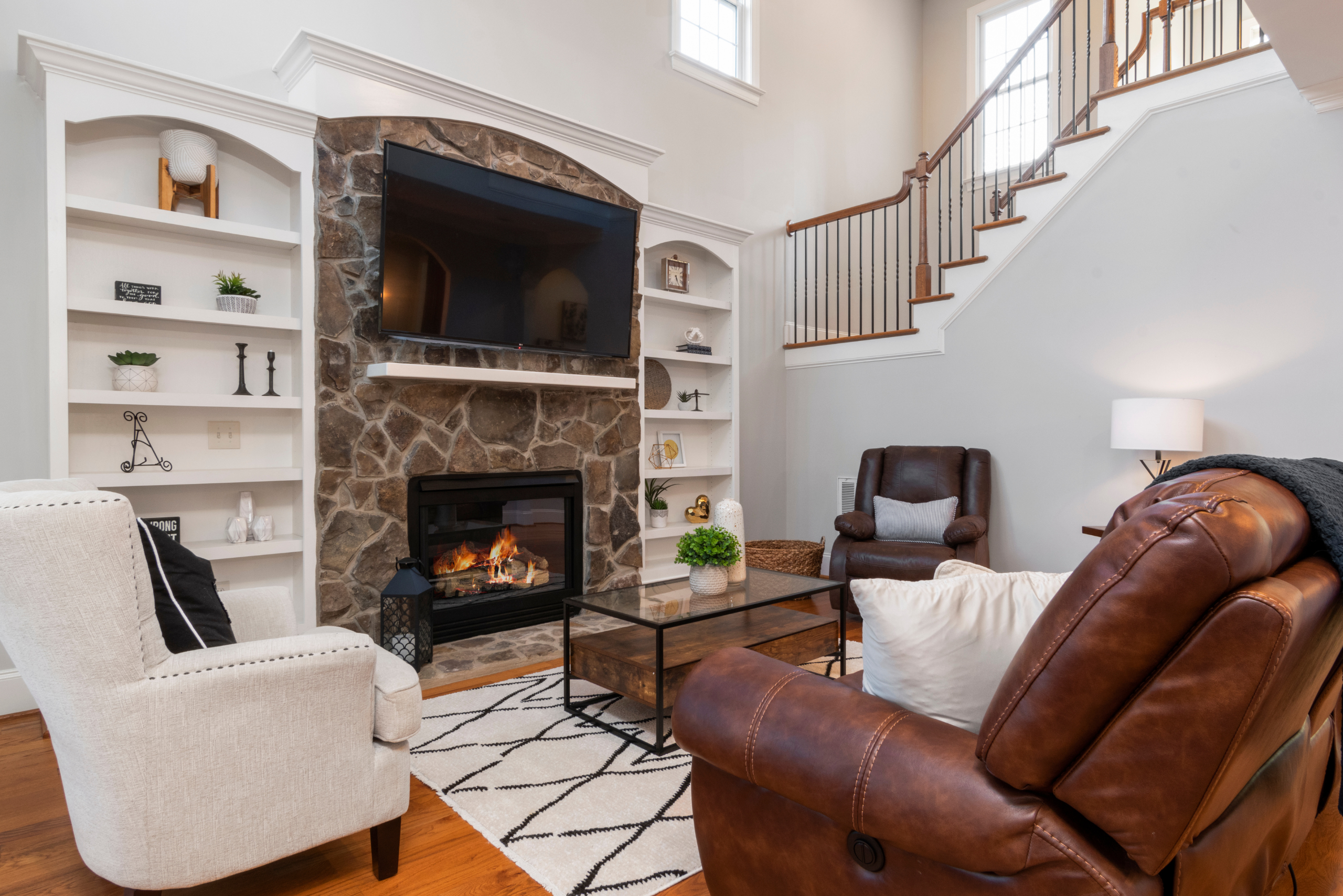 Living room with a TV mounted above stone fireplace.