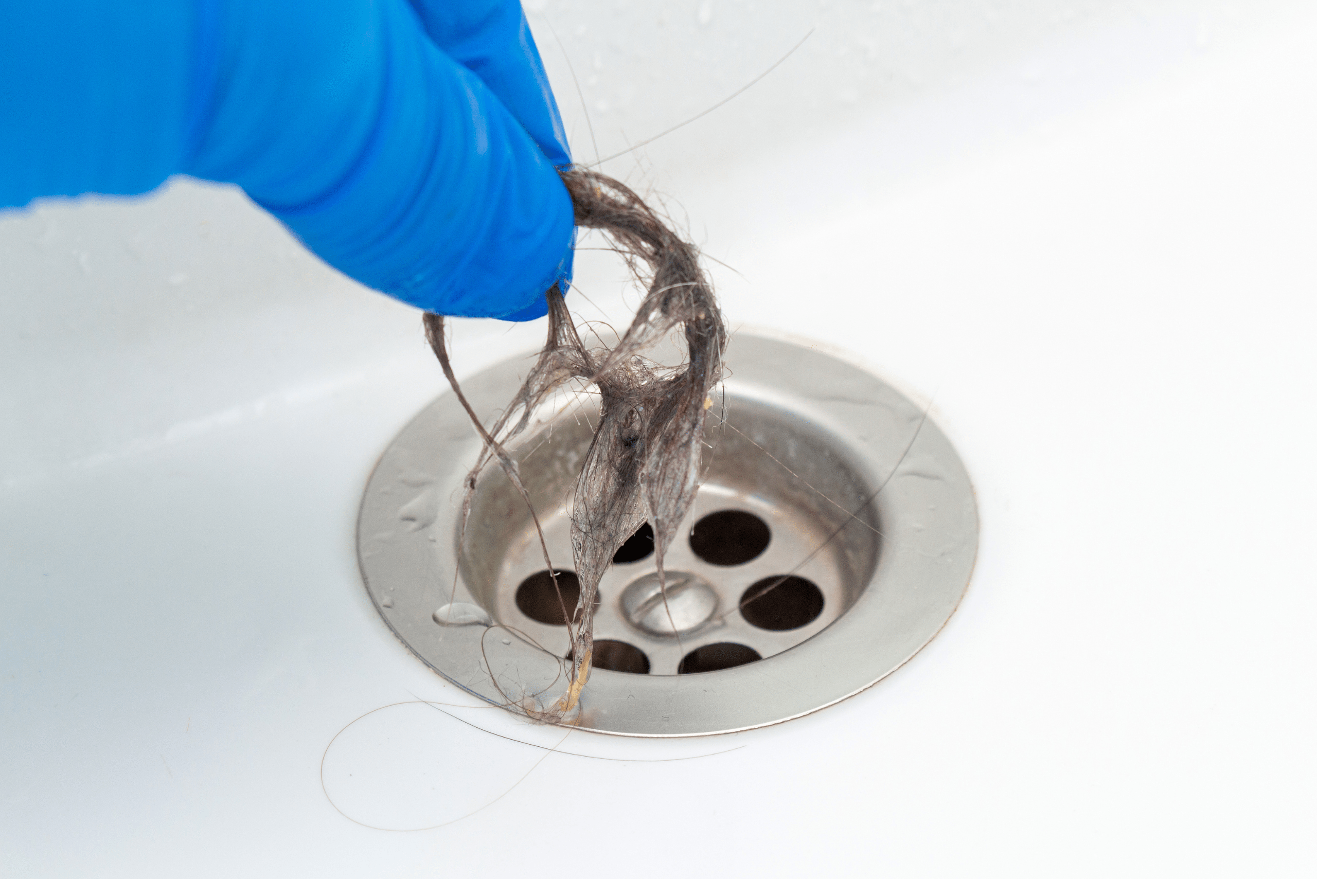 Closeup of someone's hand pulling hair from drain.