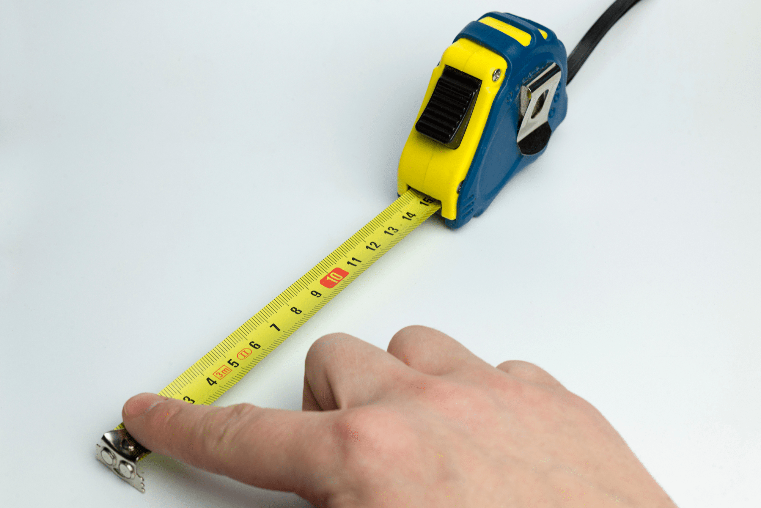 Person's hand holding the end of a measuring tape.