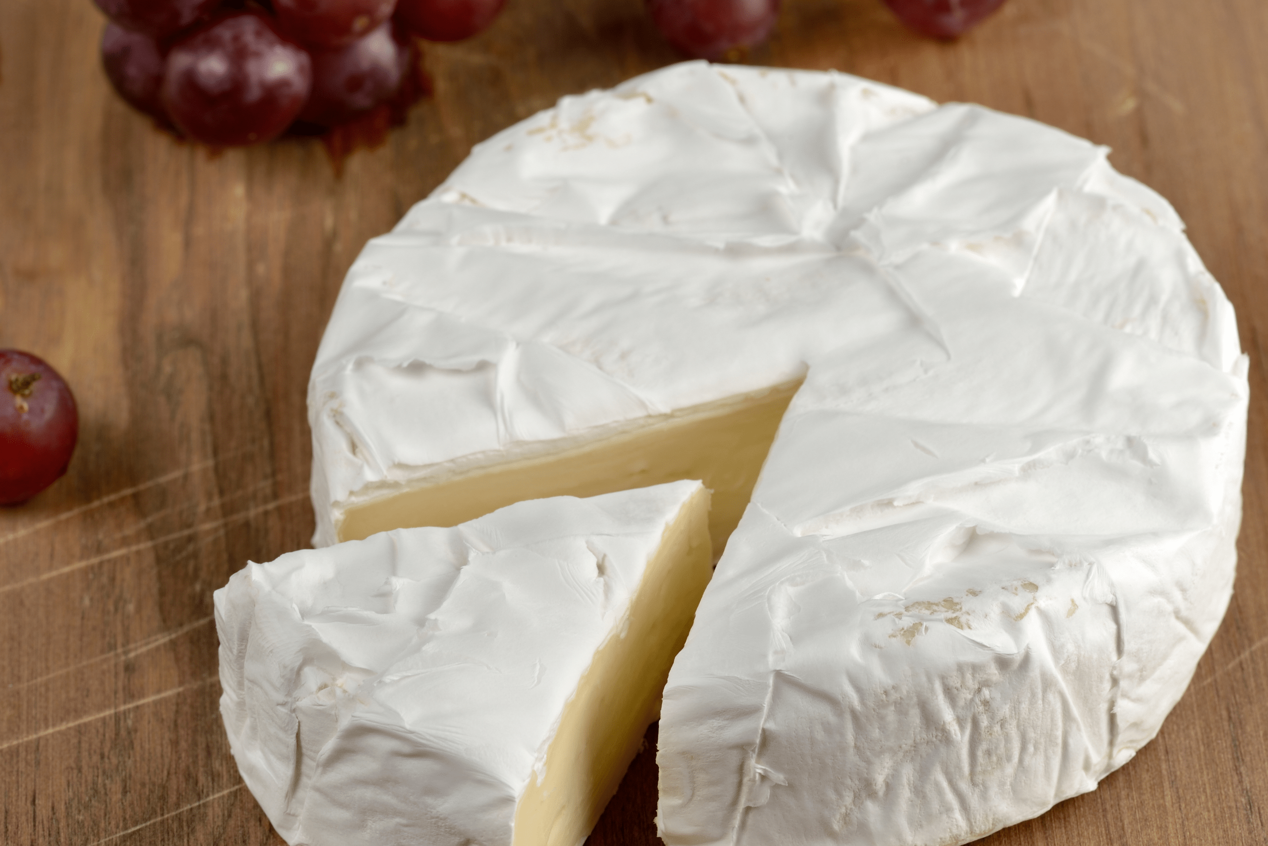 Brie cheese block with a slice cut out of it.