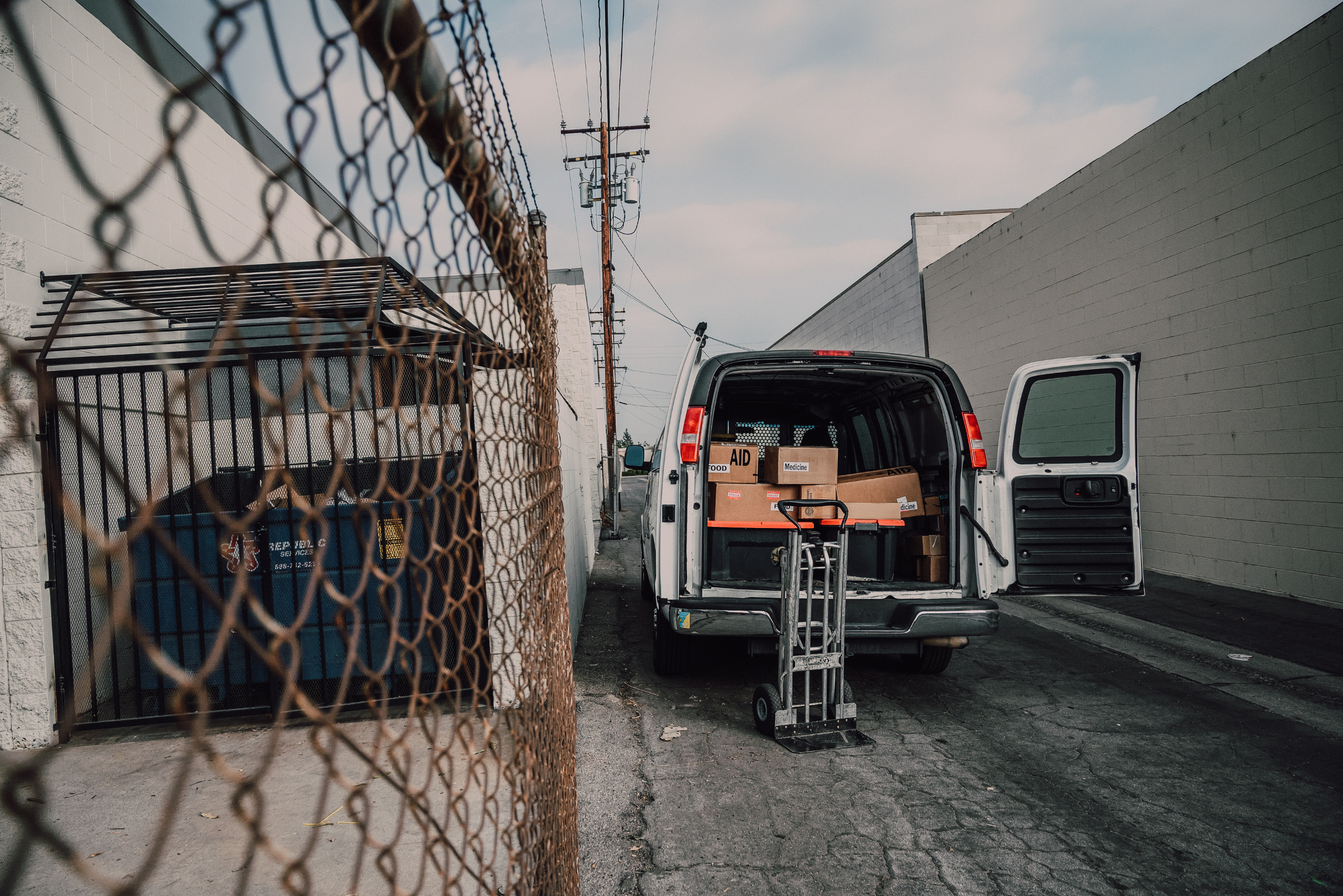 Cargo van in an alley with a moving trolly behind it.