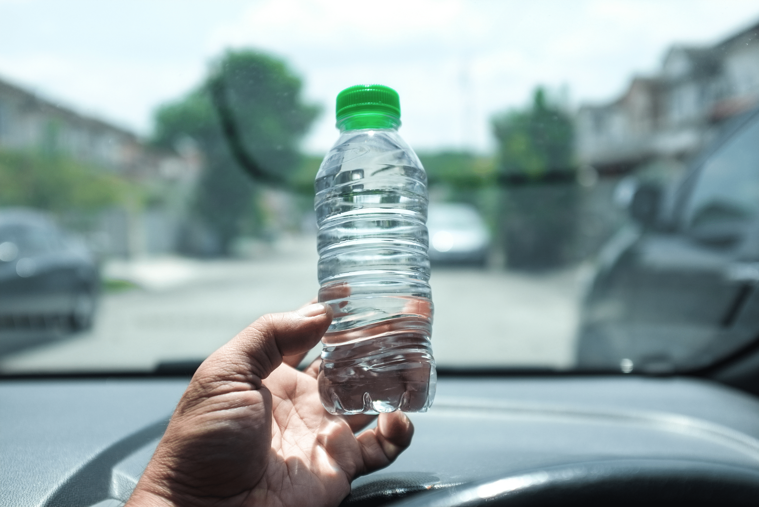 Water bottle in a car held by someone's hand.