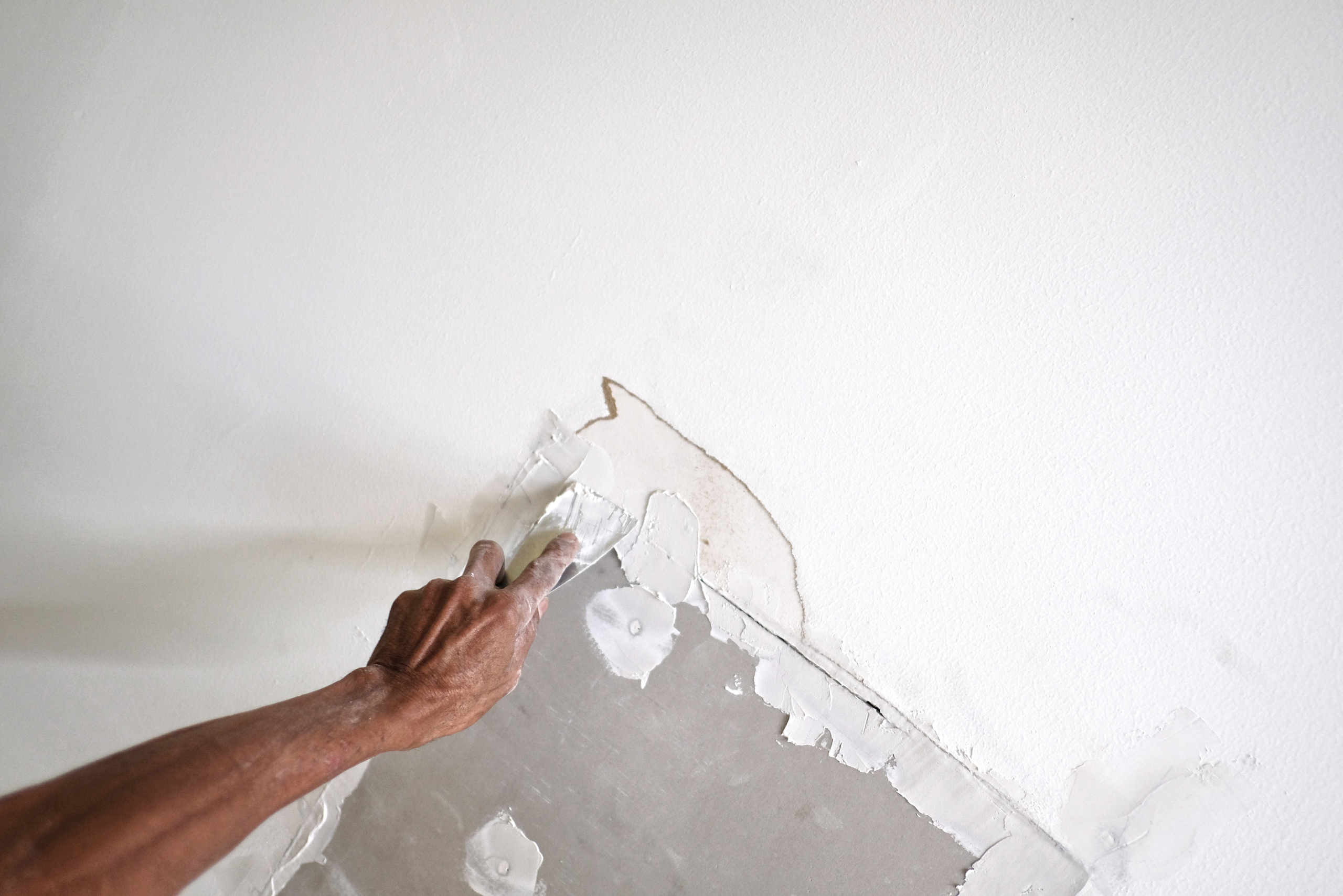 Someone's hand fixing a wall.