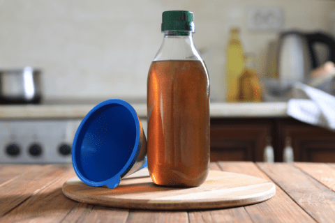 Cooking oil in bottle and a blue funnel.