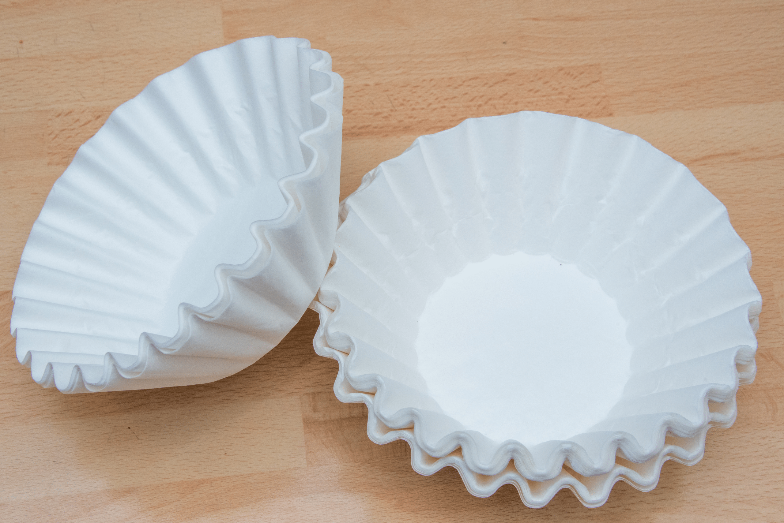 White coffee filters on wooden background.