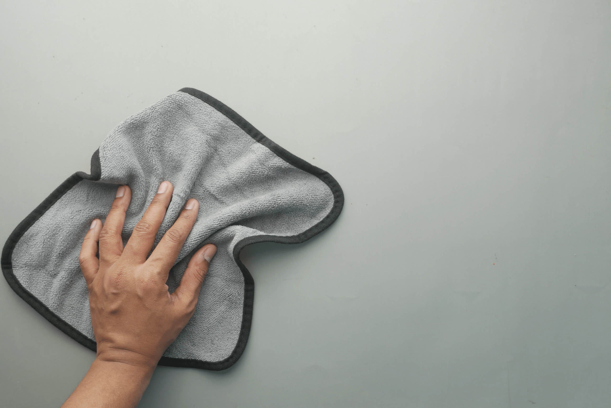 Closeup of someone's hand using a microfiber to clean wall.