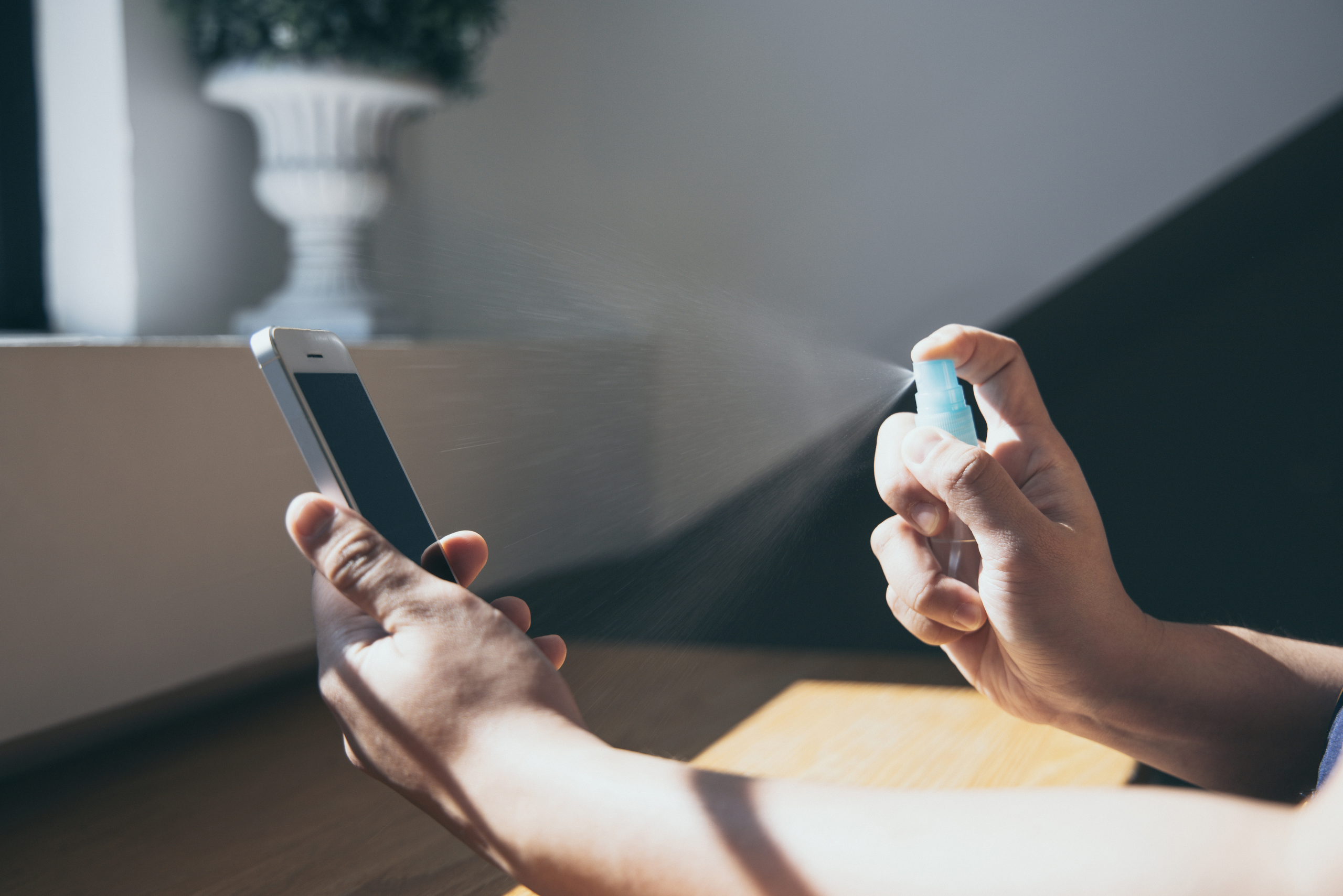 Spraying a smartphone with cleaning agent.